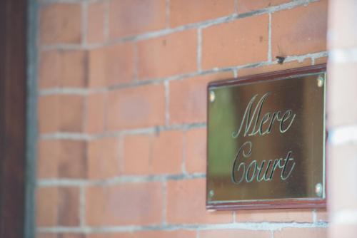 a sign on a brick wall at Mere Court Hotel in Knutsford