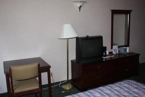 a hotel room with a bed and a tv and a lamp at Quality Inn in West Haven