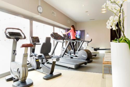 a woman exercising on a treadmill in a gym at Radisson Blu Hotel Toulouse Airport in Blagnac
