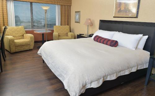 a bedroom with a large bed and two chairs at Hôtel Le Concorde Québec in Quebec City