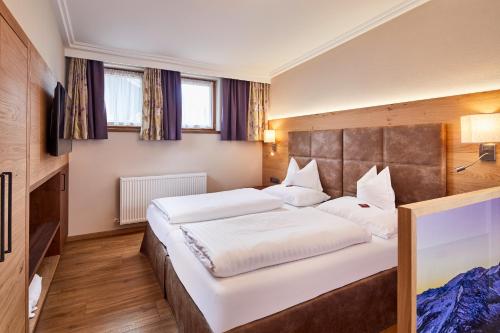 a bedroom with two beds and two windows at Hotel Neue Post in Mayrhofen