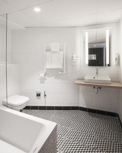 a bathroom with a tub and a sink and a toilet at ibis Styles Laval Centre Gare in Laval