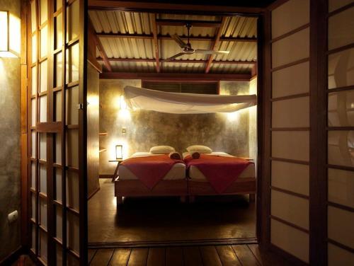 a bedroom with a bed with a red blanket at Hotel Finca Maresia in Drake