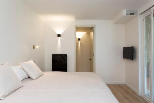 a white bedroom with a bed and a chair at Foch triomphe in Paris