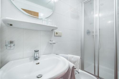 a white bathroom with a sink and a shower at Garnì Piz da L'Ander in Corvara in Badia