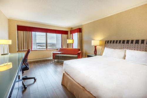 a hotel room with a large bed and a desk at Hôtel Le Concorde Québec in Quebec City