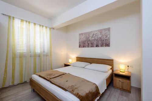 a bedroom with a bed and two lamps and a window at Apartments Robi in Trogir
