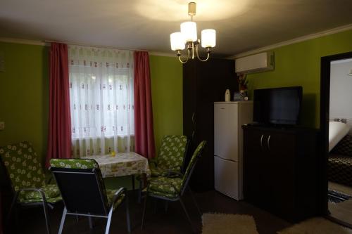 a living room with a table and chairs and a refrigerator at Mesteri Apartman in Mesteri