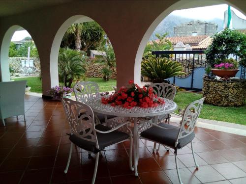 Villa Manzella piscina privata في شينيسي: طاولة وكراسي مع الزهور على الفناء