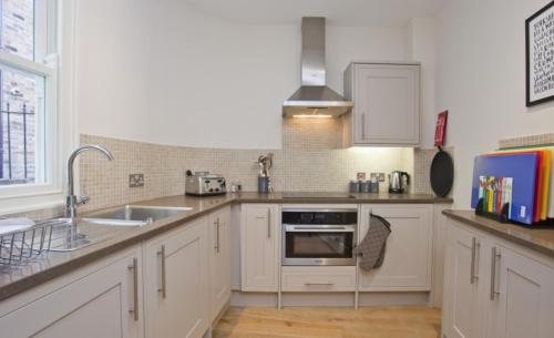 a kitchen with white cabinets and a sink at Bootes Cottage in York