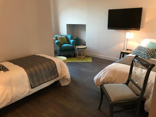 a hotel room with two beds and a flat screen tv at LOGIS Hotel-Restaurant Le Relais d'Aligre in Châteauneuf-en-Thymerais