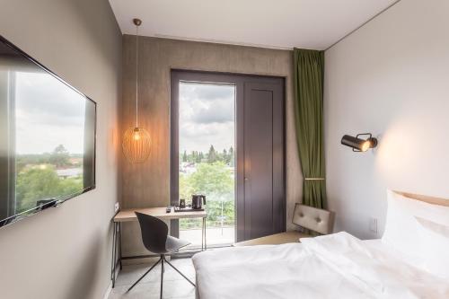 a bedroom with a bed and a desk and a window at gambino hotel CINCINNATI in Munich