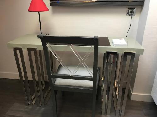 a desk with a chair and a red lamp at LOGIS Hotel-Restaurant Le Relais d'Aligre in Châteauneuf-en-Thymerais
