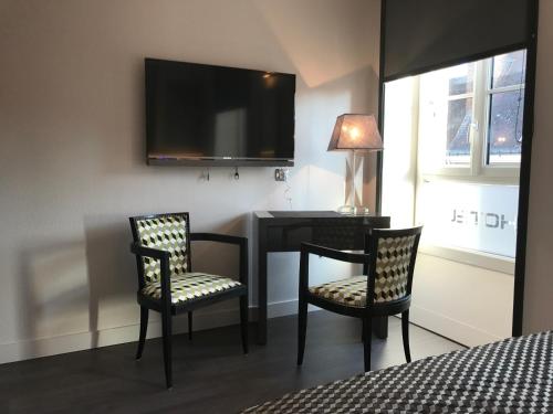 a bedroom with a desk and two chairs and a television at LOGIS Hotel-Restaurant Le Relais d'Aligre in Châteauneuf-en-Thymerais