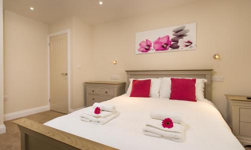 a bedroom with a large white bed with red pillows at Hill Of Oaks in Windermere