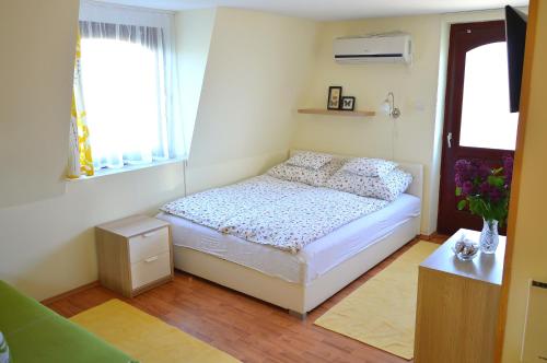 a small bedroom with a bed and two windows at Florianus Vendeghaz in Berekfürdő