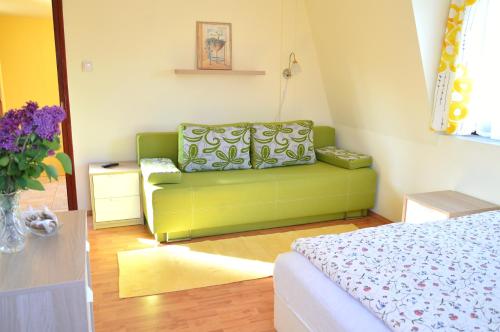 a living room with a green couch in a room at Florianus Vendeghaz in Berekfürdő