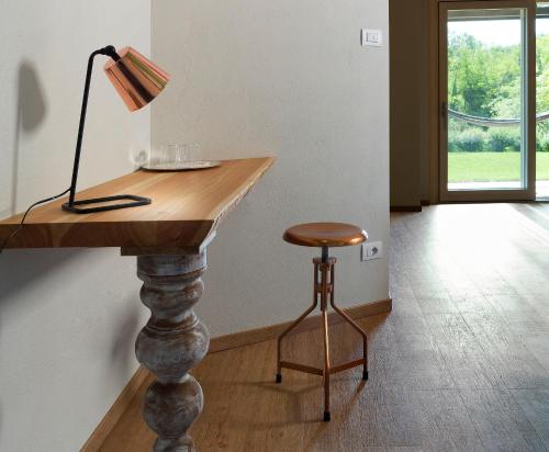 a table with a lamp and a stool in a room at Il Sambuco Innamorato in Acqui Terme