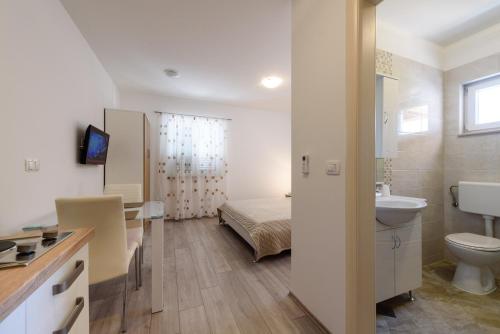 a bathroom with a sink and a toilet and a bed at Apartments Robi in Trogir