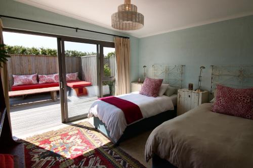 a bedroom with two beds and a balcony with a bench at Seabreeze in Kommetjie