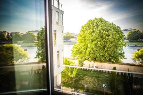 a window with a view of a building and a tree at Riverside Aparthotel Cracow in Kraków