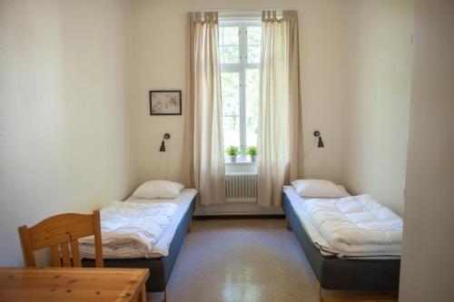 two beds in a room with a window at Ronneby Brunnspark Vandrarhem och B&B in Ronneby