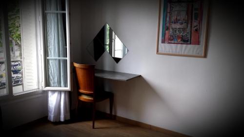 a room with a mirror and a chair next to a window at H&ocirc;tel R&eacute;sidence De Bruxelles in Paris