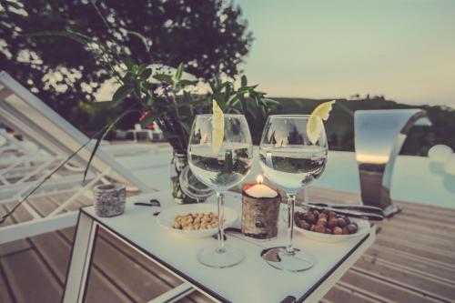 two wine glasses sitting on a table with a candle at Langhe Country House in Neive