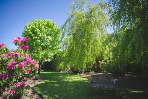 a park bench in the middle of a yard with pink flowers at Diamond Hill Country House in Waterford