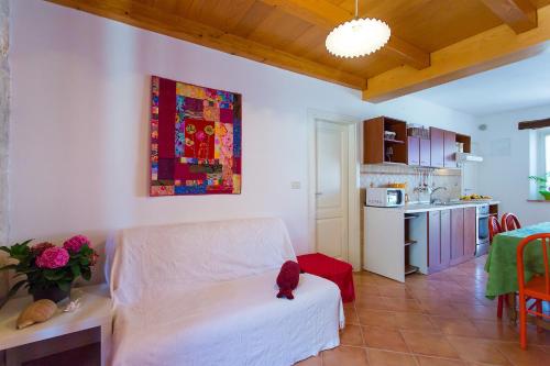 a living room with a white couch and a kitchen at Apartments Aquamarine in Funtana