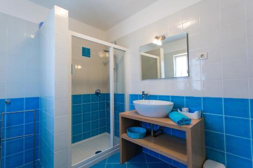 a blue and white bathroom with a sink and a shower at Apartments Aquamarine in Funtana
