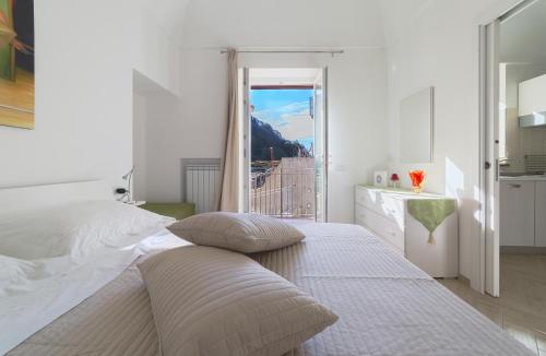 una camera bianca con un grande letto e una finestra di Casa Rosanna a Maiori