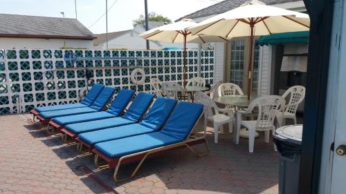 a group of blue chairs and an umbrella on a patio at The Amethyst Beach Motel in Point Pleasant Beach