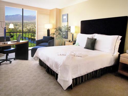 a bedroom with a large bed and a desk and chair at Pacific Palms Resort and Golf Club in La Puente