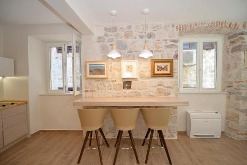 a kitchen with a table and two yellow bar stools at Apartmani Art Karampana in Kotor