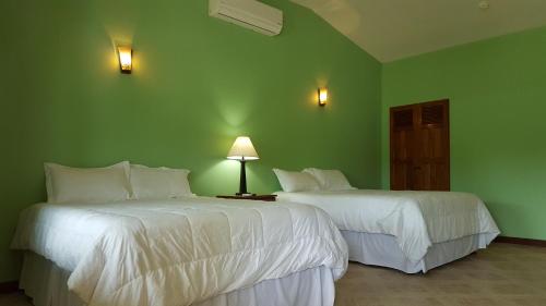 two beds in a room with green walls at Mahogany Villas in Punta Gorda