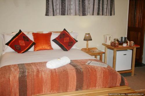 a bedroom with a bed with red and orange pillows at Colesview Guest House in Colesberg