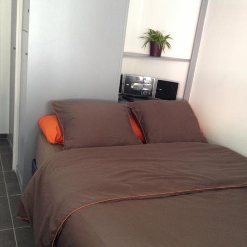 - un lit dans une petite chambre avec un oreiller orange dans l'établissement K&A Apartment, à Aulnay-sous-Bois