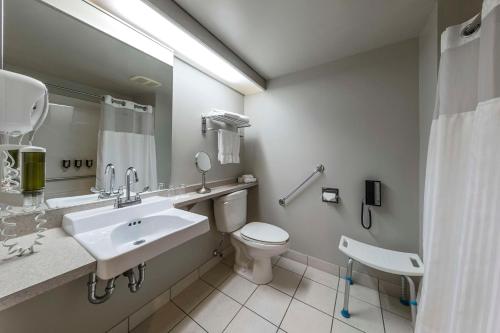 a bathroom with a sink and a toilet and a mirror at Hôtel & Suites Normandin Québec in Quebec City