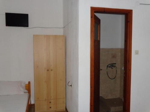 Schlafzimmer mit einem Bett und einer Holztür in der Unterkunft George Rooms in Votsi