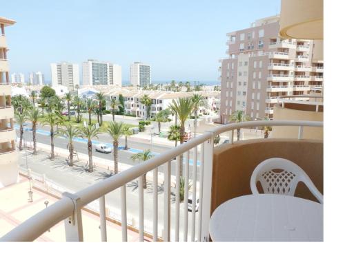 a balcony with a view of a street and palm trees at Apartamento La Manga Del Mar Menor in La Manga del Mar Menor