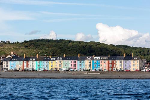 uma fila de edifícios coloridos numa praia junto à água em Seabrin em Aberystwyth