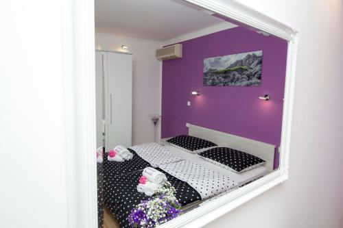 ein Schlafzimmer mit einer lila Wand und einem Bett im Spiegel in der Unterkunft Apartment Sabioncello in Split