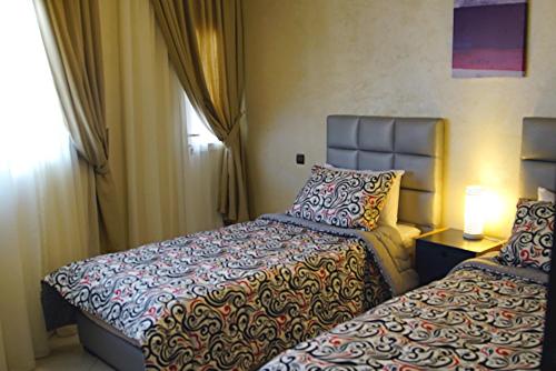 a hotel room with two beds and a window at Résidence Tamaya in Dakhla