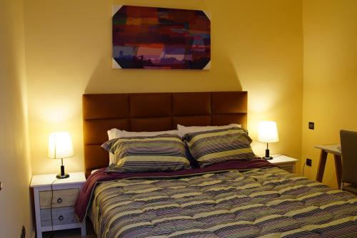une chambre avec un lit avec deux lampes et un tableau dans l'établissement Résidence Tamaya, à Dakhla