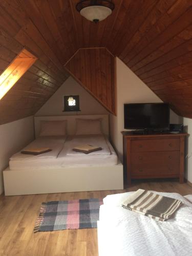 1 dormitorio con 1 cama y TV en el ático en Vörösmál Vendégház, en Balatonfüred