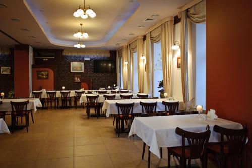 een restaurant met tafels en stoelen met witte tafelkleden bij Hotel Carskie Koszary in Zamość