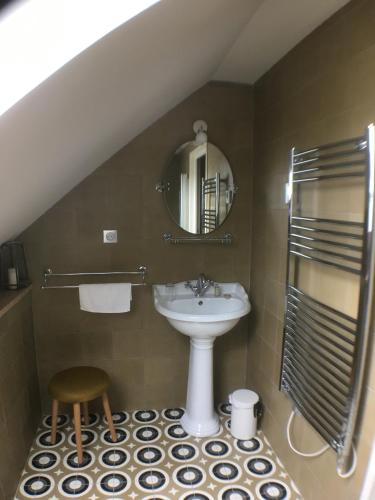 La salle de bains est pourvue d'un lavabo, d'un miroir et d'un tabouret. dans l'établissement les jardins de la Matz, à Plouër-sur-Rance