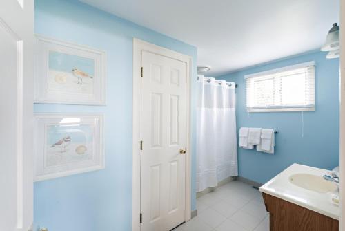 een badkamer met blauwe muren en een witte wastafel bij Chatham Tides in South Chatham