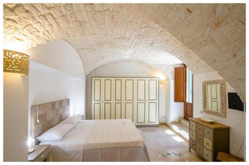1 dormitorio con cama blanca y pared de piedra en Dimora dei Pentimi, en Noci